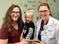 Julie A. Benard, MD, FAAP, DABOM, pediatrician with Cape Physician Associates, shares a book and a smile with Kirstan Mirgeaux and her daughter, Annie